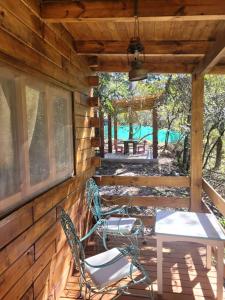 two chairs and a table on the back porch of a cabin at Cabaña Win en el Bosque, RUNA YAKU in San Lorenzo