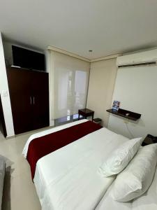 um quarto com uma grande cama branca e uma televisão de ecrã plano em Hotel Ipanema Meridian em Neiva