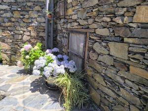 un mur en pierre avec des fleurs devant un bâtiment dans l'établissement Casa do Pastor, à Lousã