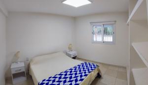 Habitación blanca con cama y ventana en Departamentos PASEO DE LAS VIÑAS, CAFAYATE, en Cafayate