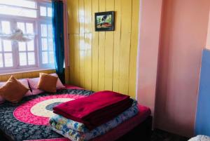 Hotel New Smriya Homestay Inn Darjeeling في دارجيلنغ: غرفة نوم مع سرير في غرفة مع نافذة