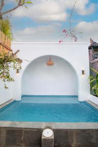 a swimming pool in a white building with blue water at Baliem CoLiving in Jimbaran