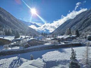 un villaggio ricoperto di neve con il sole sullo sfondo di Les Grands Montets Hotel & Spa a Chamonix-Mont-Blanc