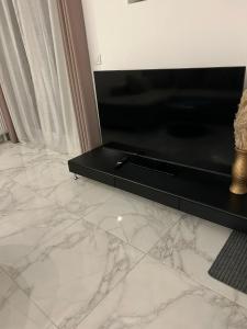 Sala de estar con suelo de mármol blanco y TV en Aurelia apartman, en Vinkovci