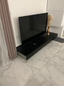 un televisor de pantalla plana sentado en un puesto negro en una habitación en Aurelia apartman, en Vinkovci