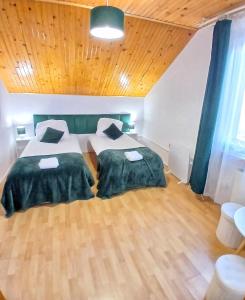 a bedroom with two beds and a wooden ceiling at KRK stop in Cholerzyn