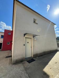 un edificio blanco con una puerta blanca y un edificio rojo en Casa Carlu Maria II, en Corte