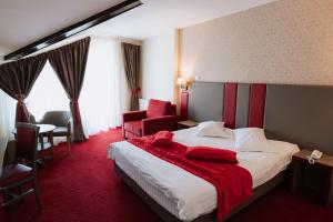 ein Hotelzimmer mit einem Bett mit einer roten Decke darauf in der Unterkunft Hotel Marea Neagra in Sinaia