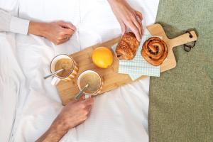 een man in bed met een dienblad met eten bij Appart Hotel Neostelia in Annecy