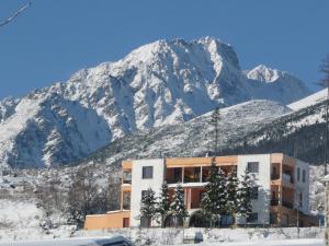 un edificio frente a una montaña nevada en Penzion Partizan, en Vysoke Tatry - Horny Smokovec