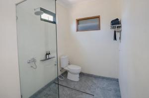 La salle de bains est pourvue de toilettes et d'une douche en verre. dans l'établissement The Akasea Villa Bali, à Ungasan