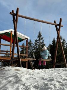 Una chica sentada en un columpio en la nieve en Sunrise Apartment Pamporovo, en Pamporovo