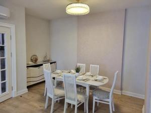 une salle à manger avec une table et des chaises blanches dans l'établissement Villa of Juoza, à Vilnius