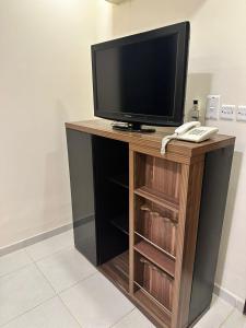 een televisie op een houten standaard met een toetsenbord en een telefoon bij شقق زوارة in Jeddah