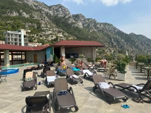 a group of people sitting in lounge chairs by a pool at Hotel PANORAMA Kruje view on the castle and the old town in Krujë