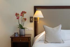 un lit avec une lampe et un vase de fleurs sur une table dans l'établissement Suvretta House, à Saint-Moritz