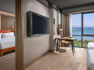 Mövenpick Hotel Istanbul Marmara Sea في إسطنبول: غرفة فندقية بتلفزيون وطاولة مع سرير