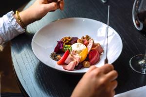 a person holding a plate of food on a table at Van der Valk Hotel Brussels Airport in Diegem