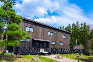 ein großes Holzgebäude mit Bäumen im Hintergrund in der Unterkunft FamA in Nakafurano