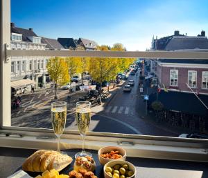 un tavolo con due bicchieri di champagne e cibo su una finestra di Cooth's Residence a Breda