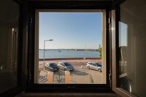 ein Fenster mit drei Autos auf einem Parkplatz in der Unterkunft Duplex em Baía do Seixal in Seixal