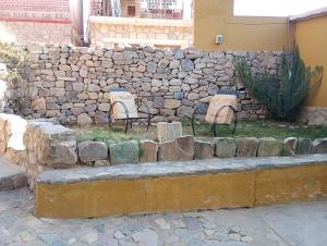 pared de piedra con 2 sillas y banco de piedra en La Pirquita, en Tilcara