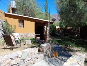 una casa con una pared de piedra y una silla en un patio en La Pirquita, en Tilcara