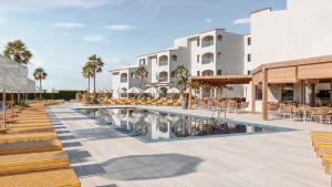 um resort com piscina, mesas e cadeiras em Caramelo Marina Calan Bosch em Cala'n Bosch