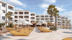 um hotel com uma fila de cadeiras e guarda-sóis em Caramelo Marina Calan Bosch em Cala'n Bosch