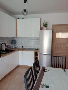 cocina con armarios blancos, mesa y nevera en Pokoje nad Radunią, en Pruszcz Gdański