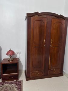 einen Holzschrank in einem Zimmer mit einem Tisch in der Unterkunft Michenzani Flat in Zanzibar City