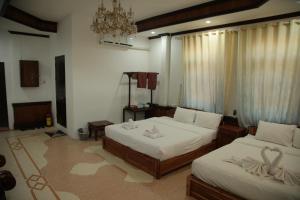 a bedroom with two beds and a chandelier at Villa KiengKham晶康民宿 in Luang Prabang