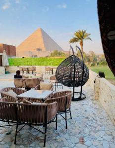 eine Terrasse mit Tischen und Stühlen mit einer Pyramide im Hintergrund in der Unterkunft Golf Pyramids View in Kairo