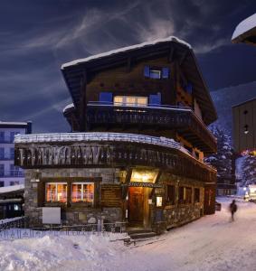 una baita di tronchi nella neve di fronte a un edificio di Guesthouse by the rex a Zermatt