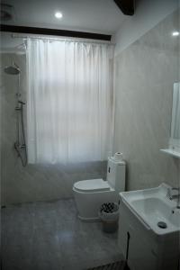 a white bathroom with a toilet and a sink at Villa KiengKham晶康民宿 in Luang Prabang