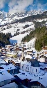 uma pequena cidade coberta de neve com uma igreja em Aparthotel Bergtraum em Mühlbach am Hochkönig