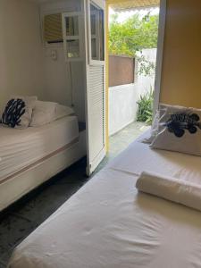 two beds in a room with a window at Peixe Crew Centro in Búzios