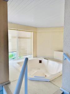 una gran bañera blanca en una habitación con ventana en Mandai Apartamentos, en Cabo Frío