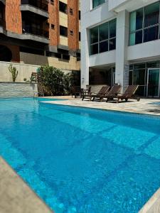 una gran piscina azul frente a un edificio en Mandai Apartamentos, en Cabo Frío