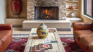 a living room with a fireplace and a vase on a table at The Lodge at Santa Fe in Santa Fe