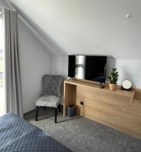 - une chambre avec un lit, une télévision et une chaise dans l'établissement Baltic Apartamenty, à Jastrzębia Góra