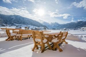 einen Holztisch und Stühle im Schnee in der Unterkunft COOEE alpin Hotel Dachstein in Gosau