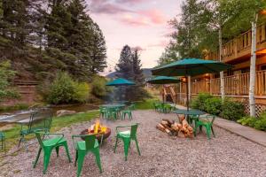 un foyer extérieur avec des chaises vertes, des tables et des parasols dans l'établissement Best Western Rivers Edge, à Red River