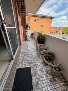 een balkon met een tegelvloer en potplanten bij Alison's central apartment in Cabramatta