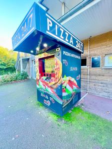 un puesto de pizza frente a un edificio en L’entrelacs, en Équemauville