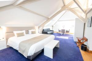 een slaapkamer met een wit bed en een blauw tapijt bij Hotel d'Angleterre in Châlons-en-Champagne