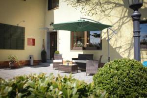 eine Terrasse mit Stühlen und einem grünen Sonnenschirm in der Unterkunft Hotel Rosenhof Garni in Pegnitz