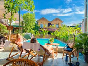 two women sitting in chairs by a swimming pool at An Nam Ơi House Homestay in Tam Coc in Vũ Lâm