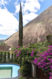 un jardin avec une piscine et des fleurs dans l'établissement Chalé Rosa do Vale, à Petrópolis