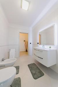 Baño blanco con lavabo y aseo en Swamyhome Aereoportobaripalese, en Bitonto